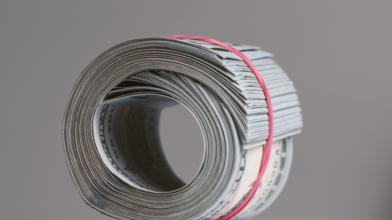 一卷一百美元的钞票用橡皮筋绷紧。视频下载