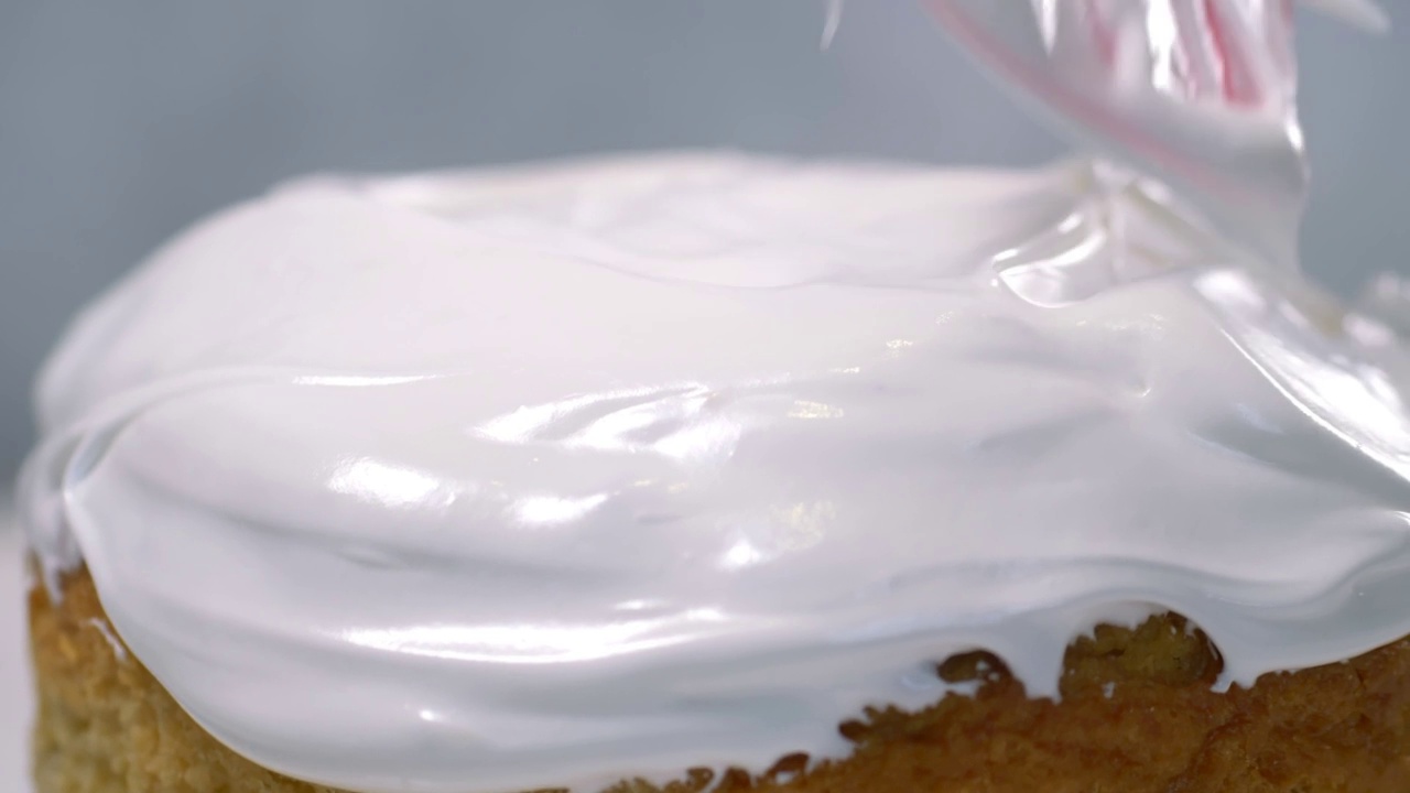特写镜头。一把厨房铲在美味的东正教复活节面包上涂上糖霜，这是一种传统的俄罗斯和乌克兰的东欧复活节蛋糕。灰色背景上覆有白色糖霜的复活节蛋糕。视频素材