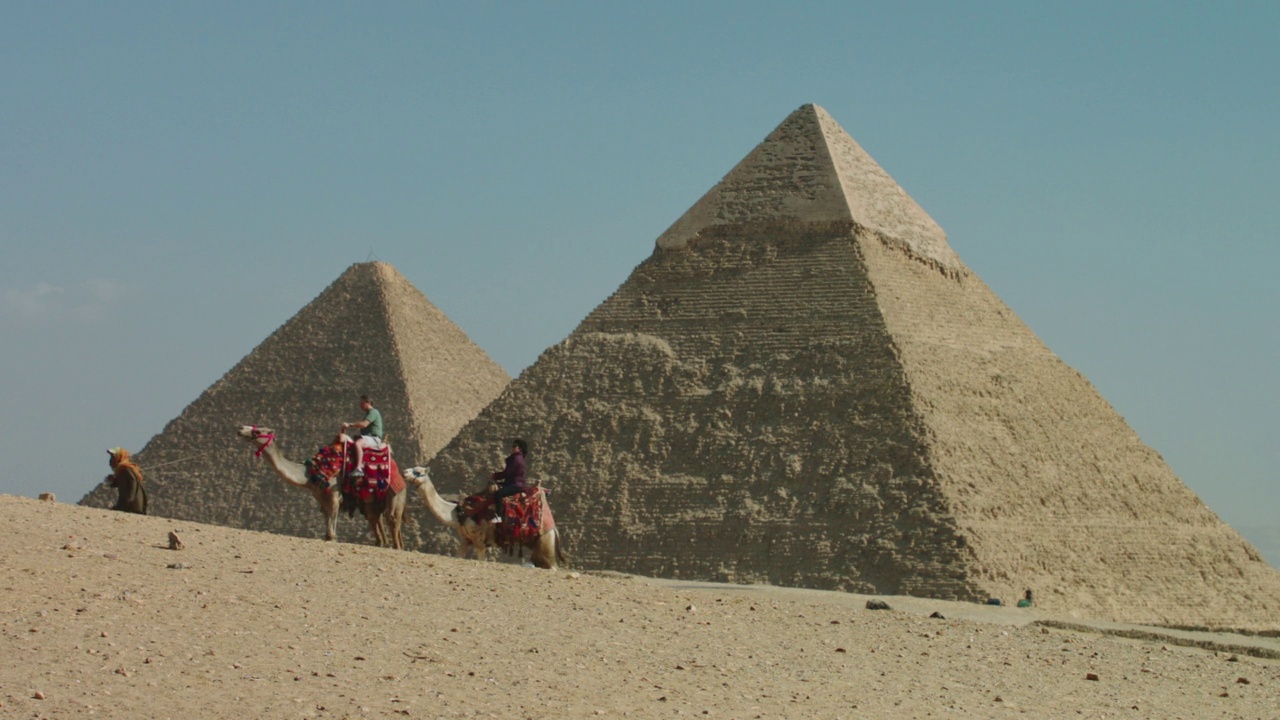 在吉萨金字塔骑骆驼的游客。视频素材
