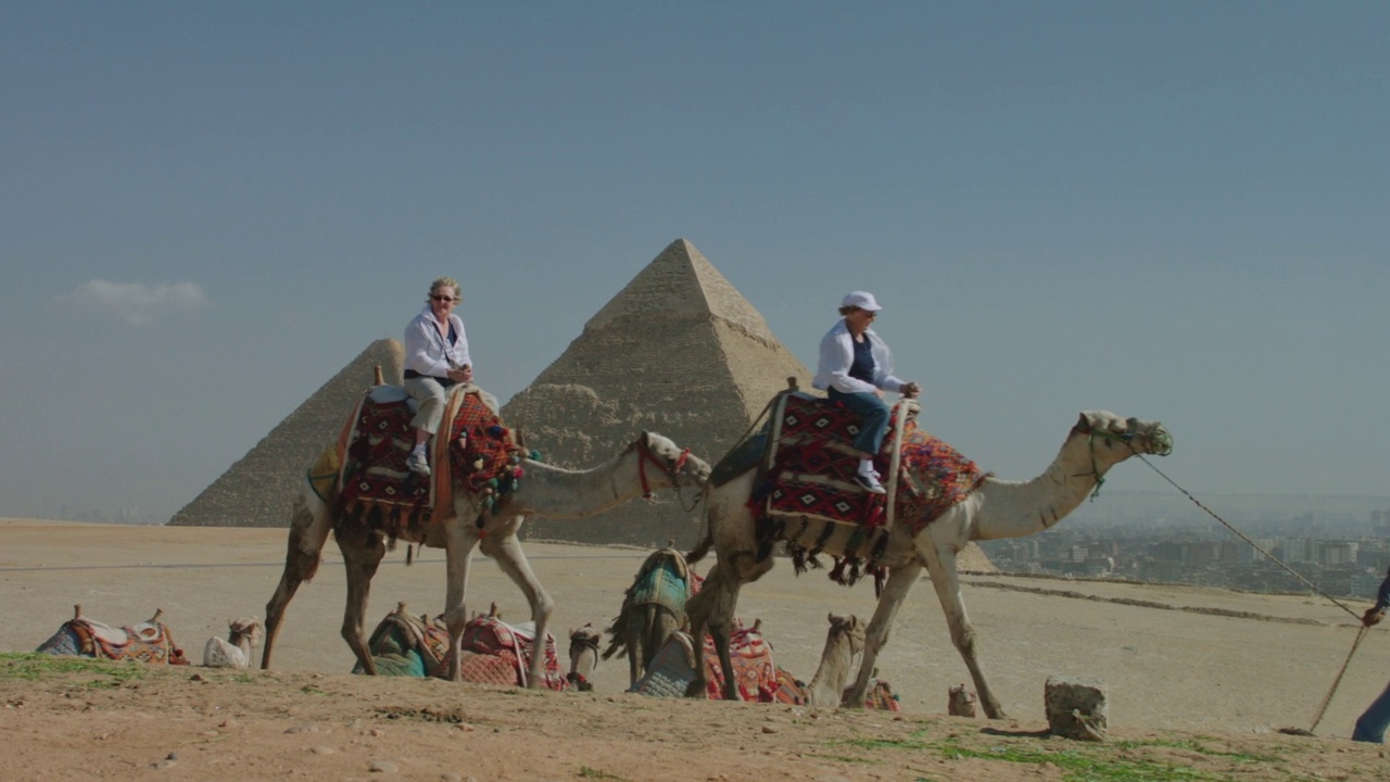 在吉萨金字塔骑骆驼的游客。视频素材