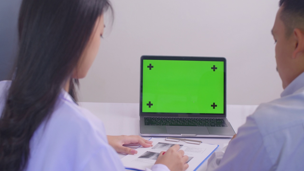亚洲女医生和男病人在诊所用笔记本电脑绿屏讨论x光结果视频素材