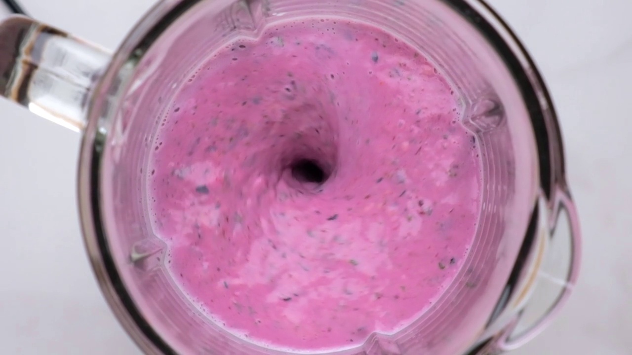 蓝莓奶昔或奶昔混合在搅拌机和飞溅。前视图。慢动作视频素材