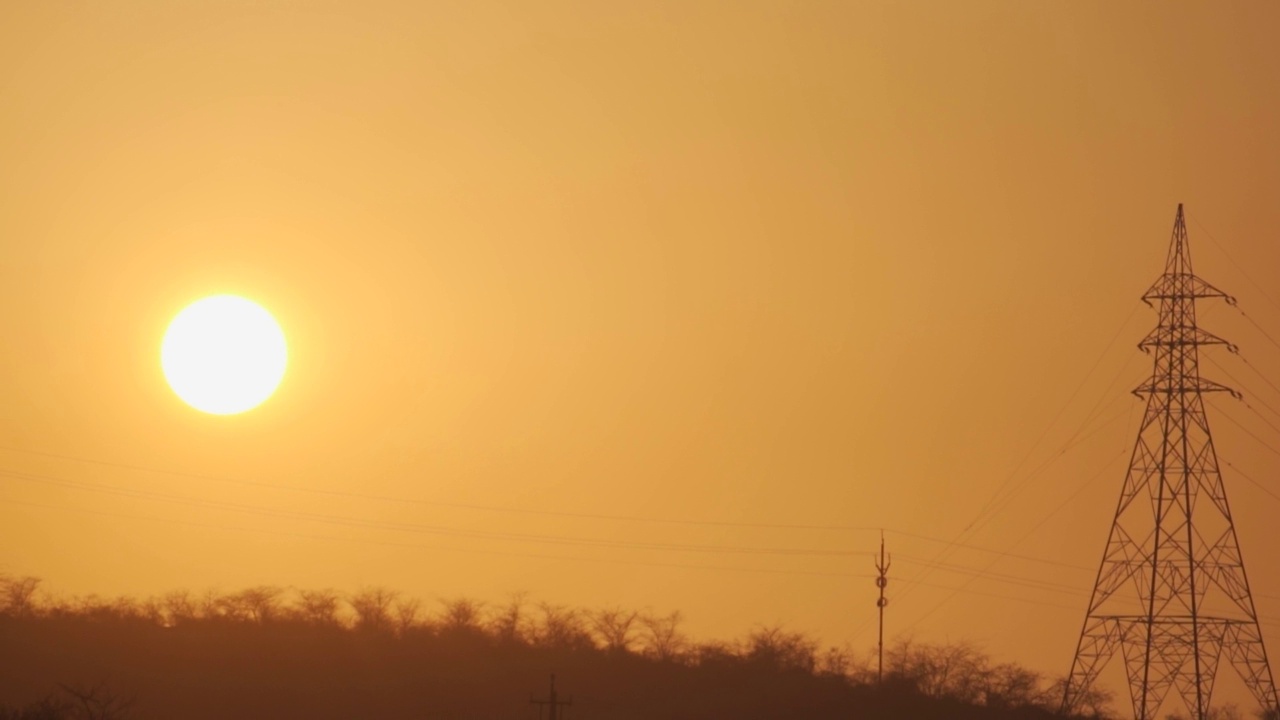 在印度古吉拉特邦的Wankaner，夕阳下电塔的剪影。日落时分，输电塔旁边的太阳。能源的背景。视频素材
