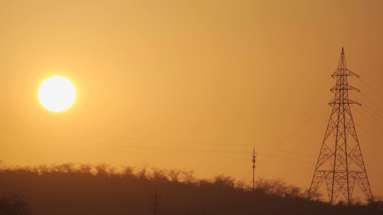 在印度古吉拉特邦的Wankaner，夕阳下电塔的剪影。日落时分，输电塔旁边的太阳。能源的背景。视频素材
