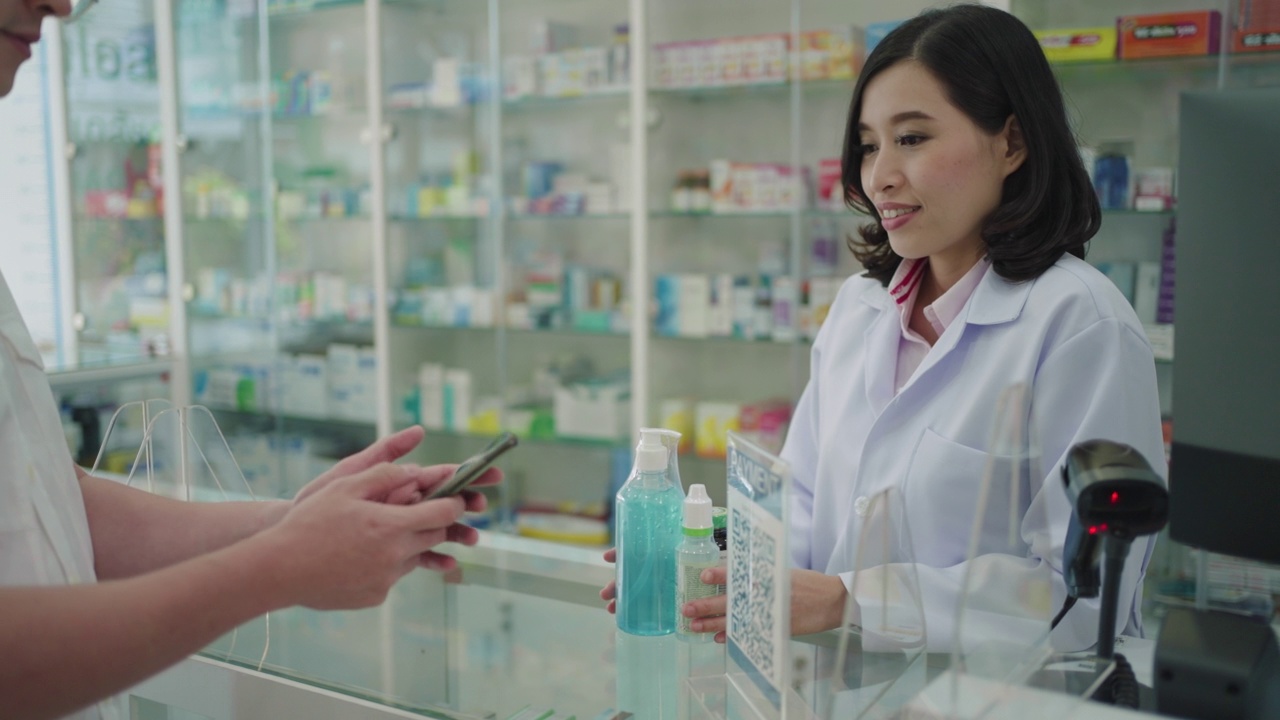 亚洲男子顾客在药店扫描支付二维码购买药品。视频下载