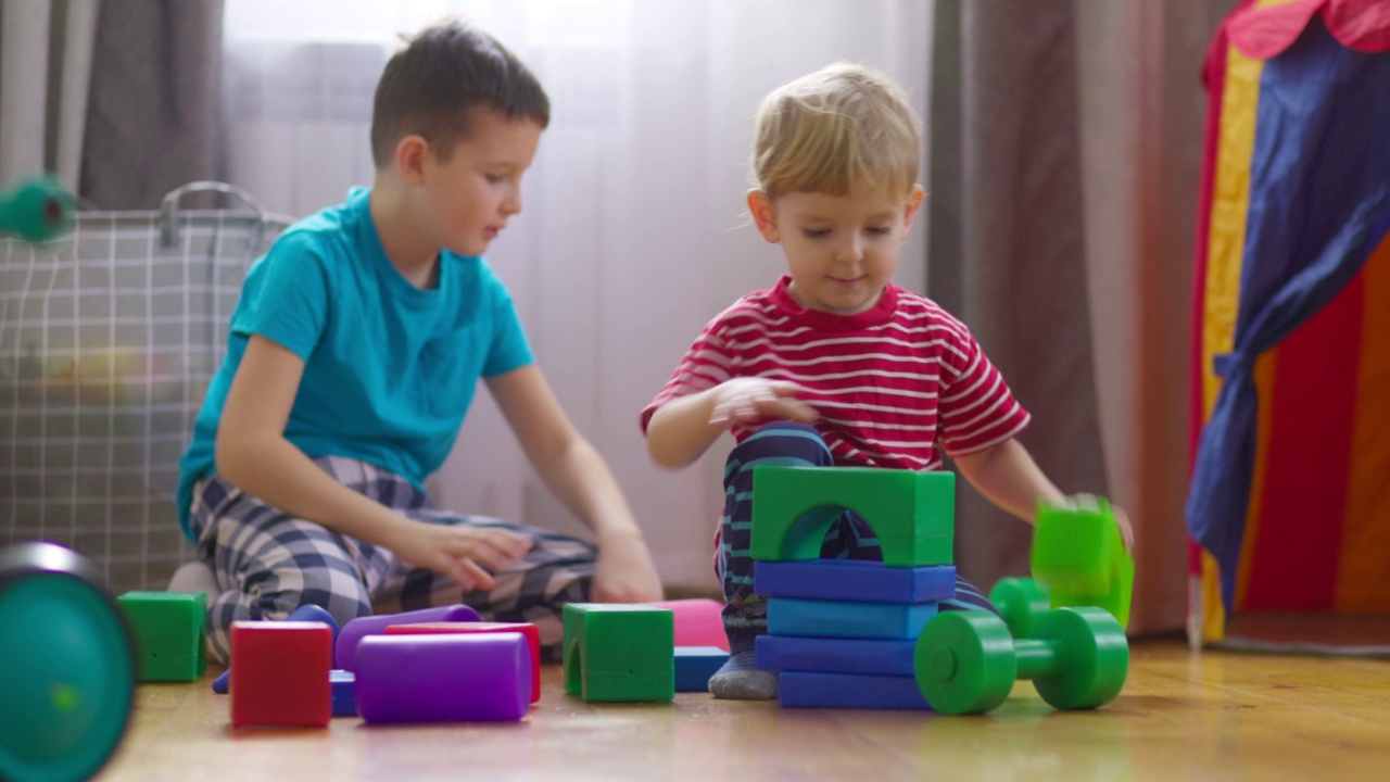 孩子们和孩子们在地板上玩积木。建造一个立方体塔。儿童益智玩具视频下载