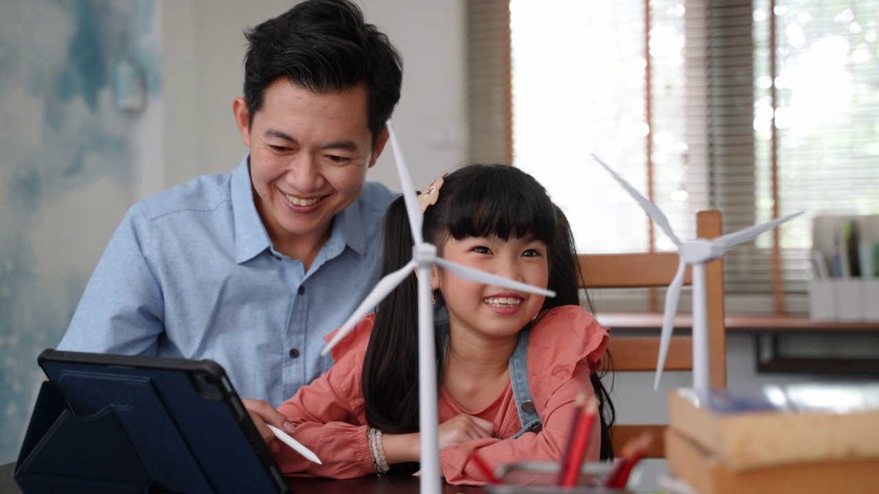 亚洲单亲父亲用风力发电机模型教女儿清洁能源的可持续性视频素材