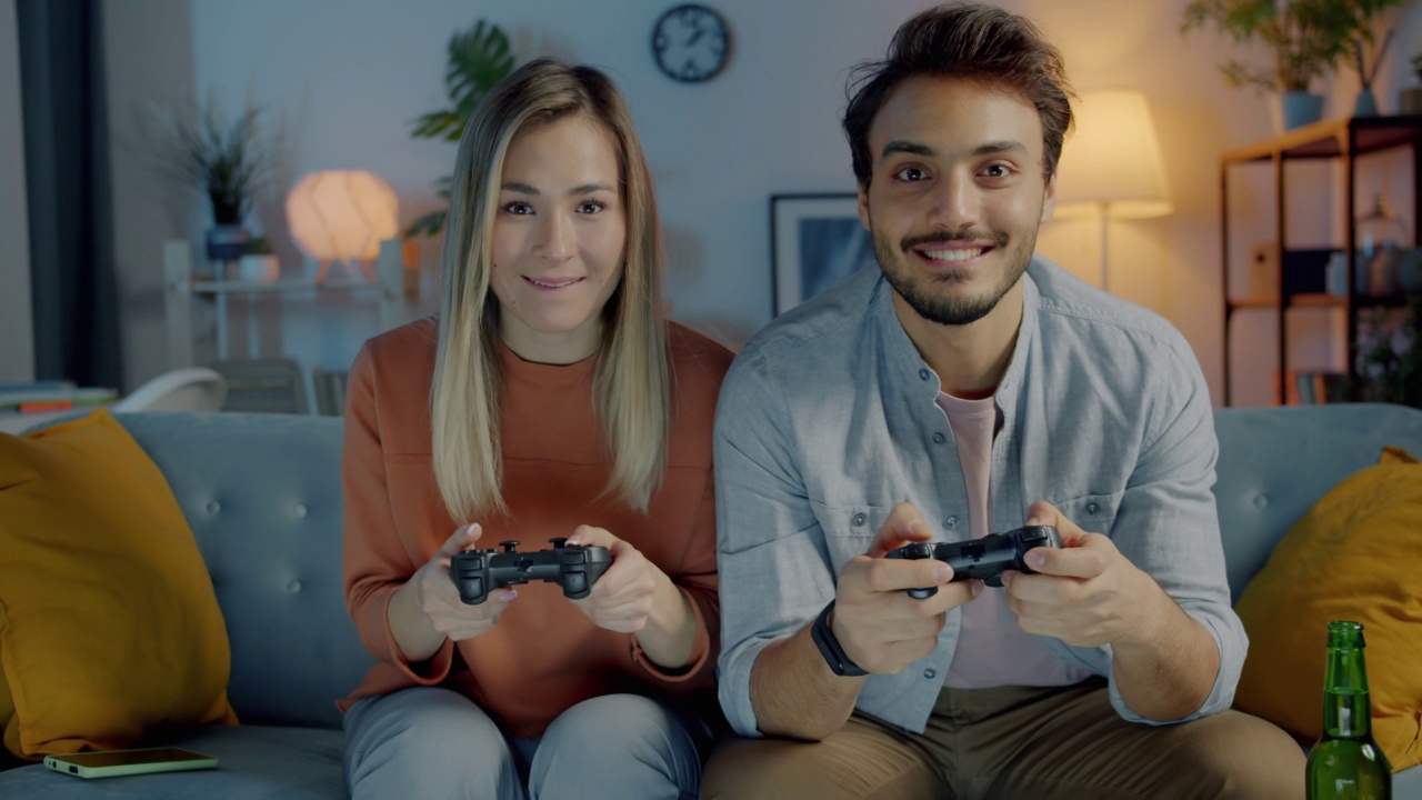 快乐的男人和女人玩视频游戏的肖像，晚上在公寓里玩得很开心视频素材