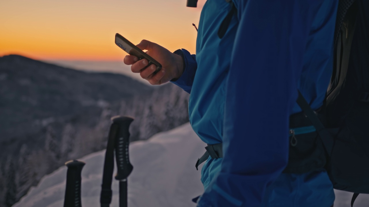 女徒步旅行者在黄昏时分在山里使用她的智能手机视频下载
