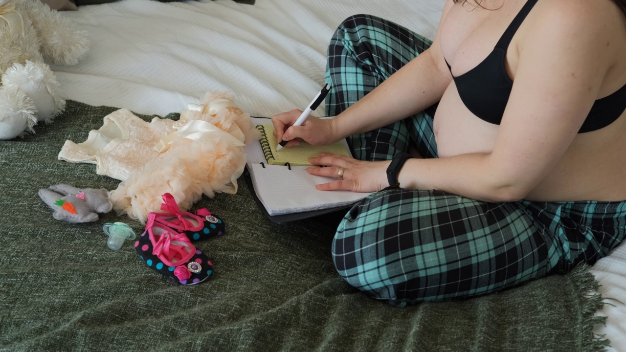 孕妇坐在床上做笔记视频素材