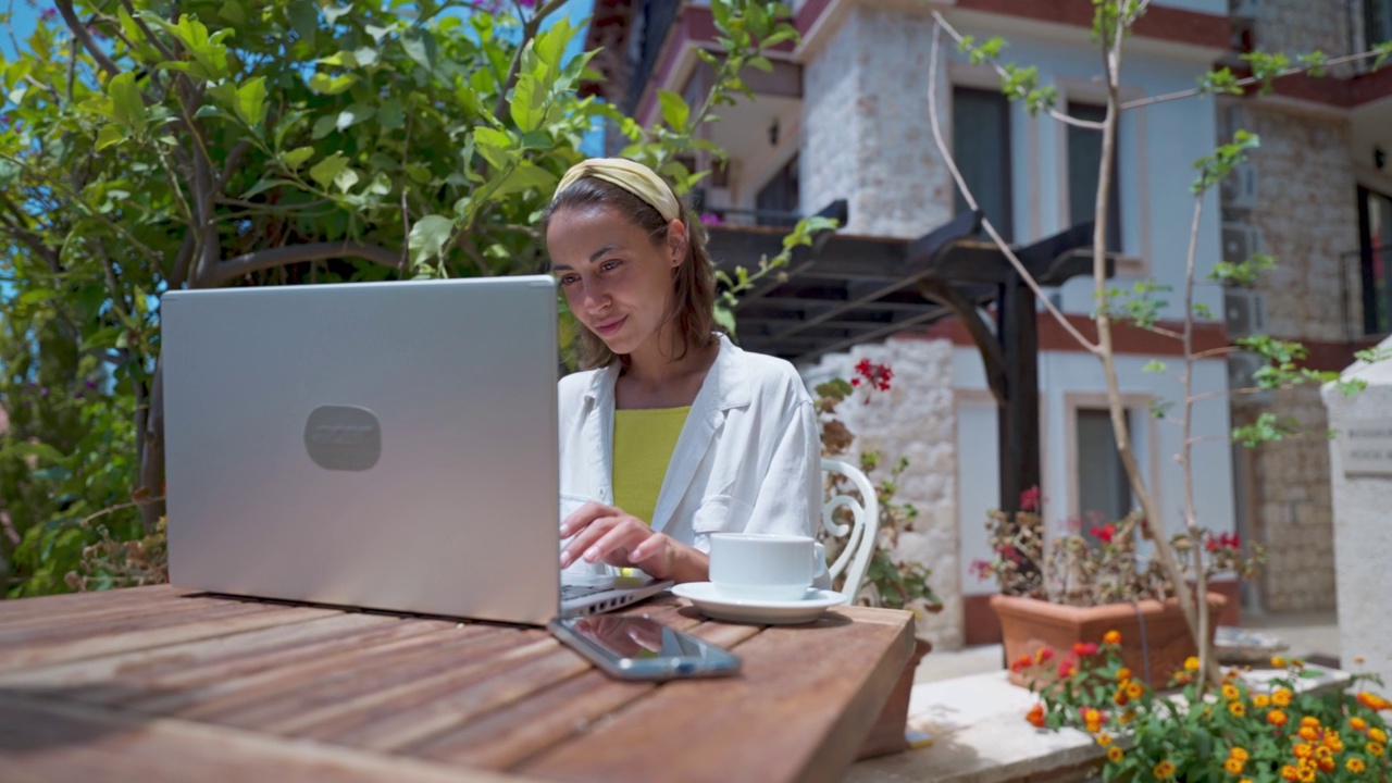 万向镜头镜头特写美丽的女人喝咖啡享受使用笔记本电脑上网在阳光明媚的一天在度假热带咖啡馆视频素材