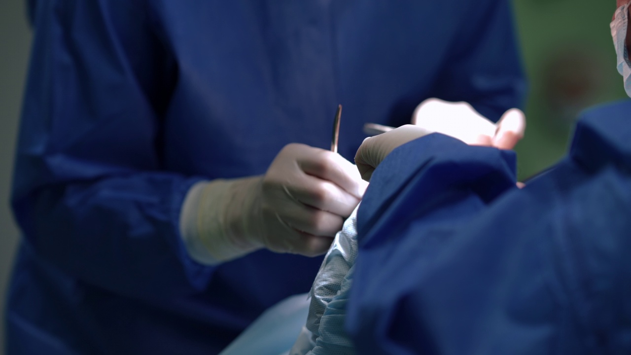 外科医生和护士的手和手术器械在手术室里做手术。无法辨认的专业白人男女在医院室内帮助病人。缓慢的运动。视频素材