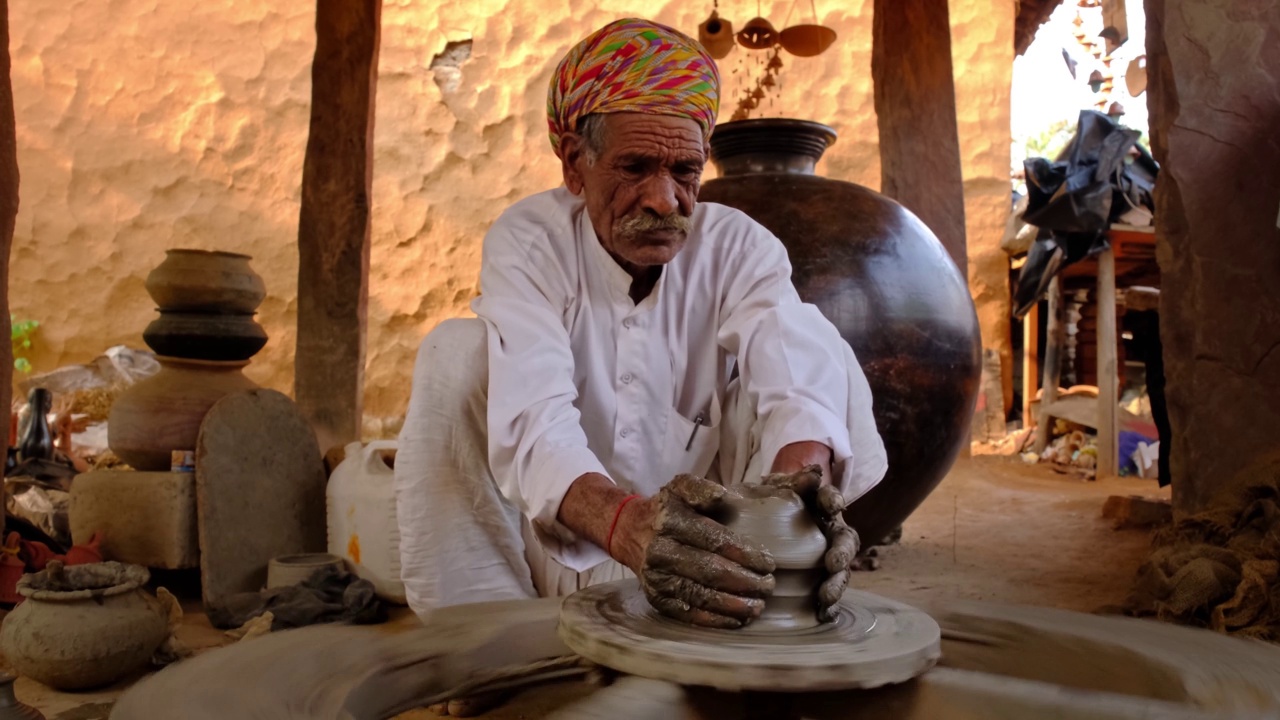 印度陶工在工作:投掷陶工轮和塑造陶瓷器皿和陶土制品:陶艺车间的罐子。经验丰富的主人。来自印度拉贾斯坦邦乌代普尔什帕格拉姆的手工工艺品视频下载