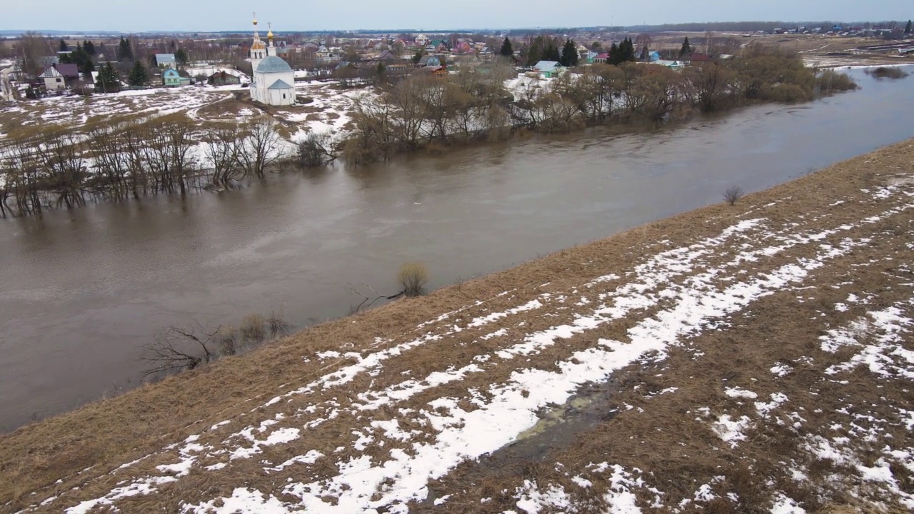 肮脏的河水夹杂着灰色的水，残留的雪堆在岸边。视频素材