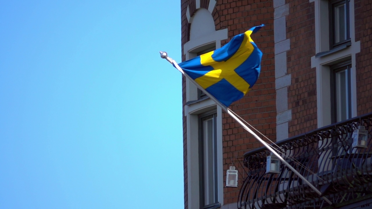 封锁慢镜头拍摄的瑞典国旗在阳光明媚的一天在阳台上挥舞-斯德哥尔摩，瑞典视频下载