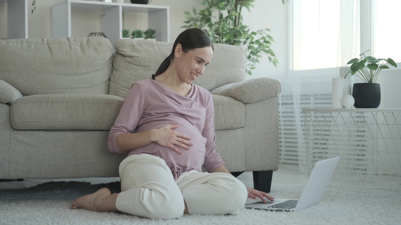 孕妇在家里的地毯上使用笔记本电脑视频素材