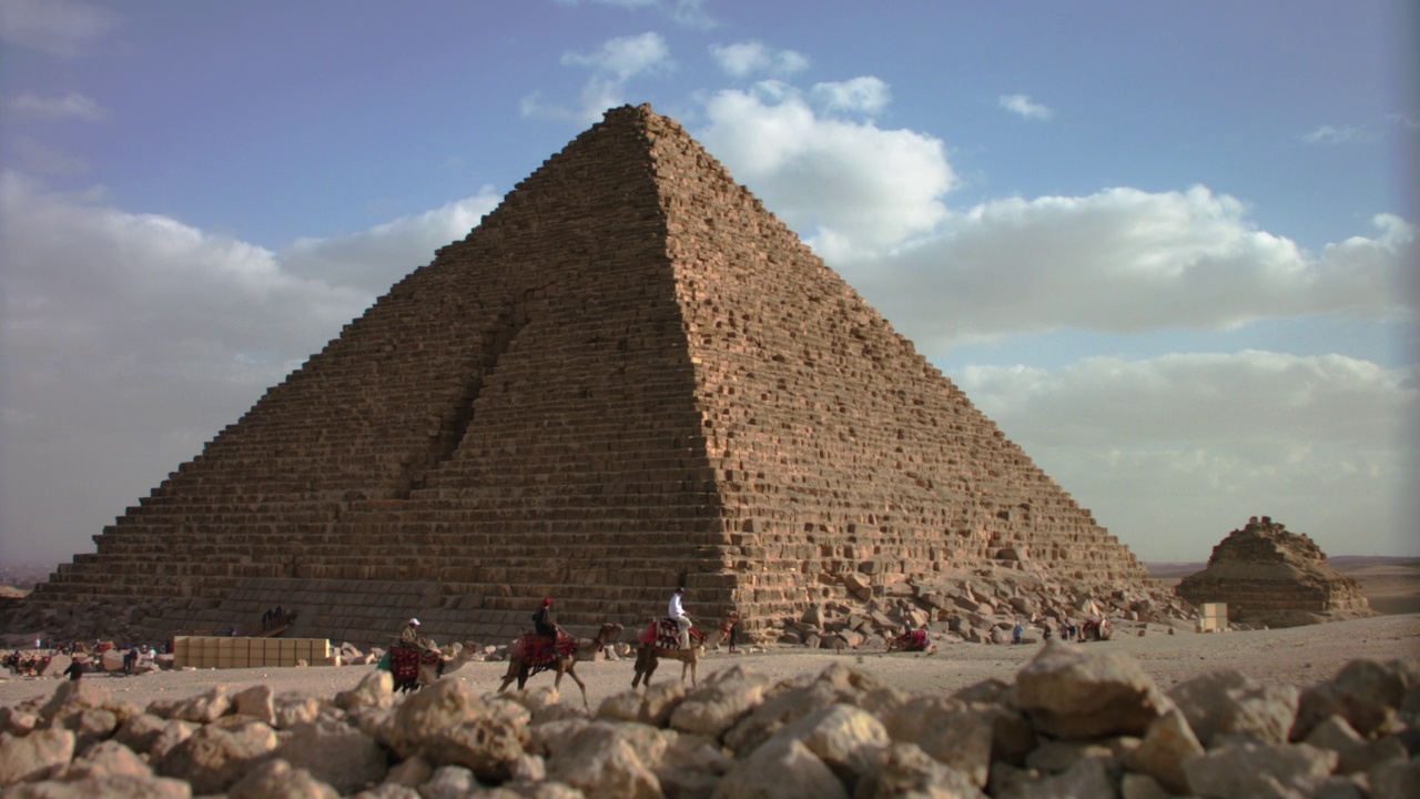 屠女士游客骑骆驼在金字塔前。视频下载