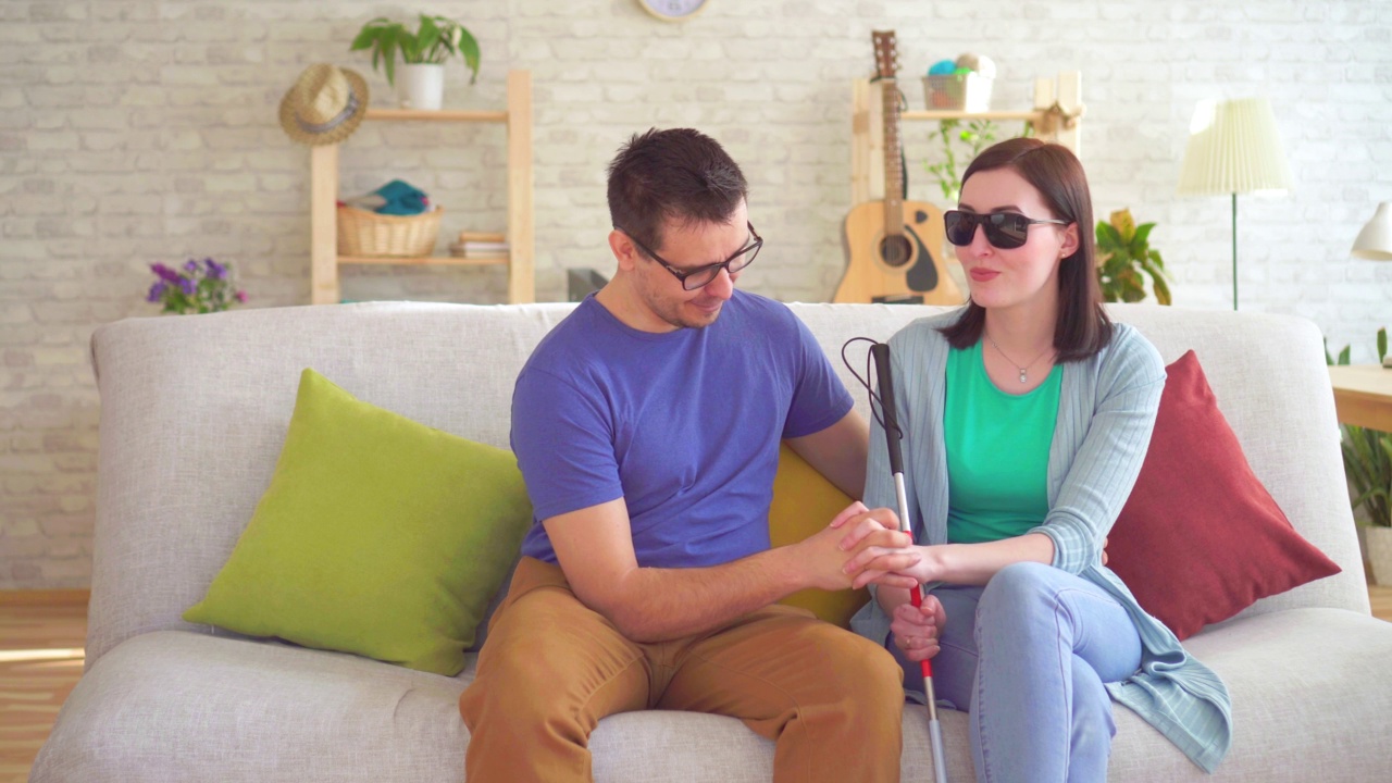 一个年轻人和一个坐在沙发上的残疾盲人女人调情视频下载
