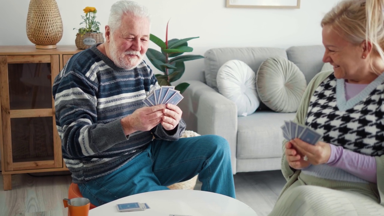 快活的爷爷藏起牌来，和老伴在家里玩牌，开怀大笑视频素材
