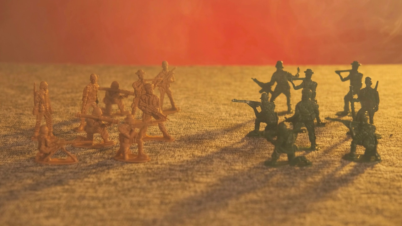 黄色和绿色的塑料玩具士兵组成的军队在烟雾中相对地站着，背景是闪烁的红光。军事作战行动的概念视频下载