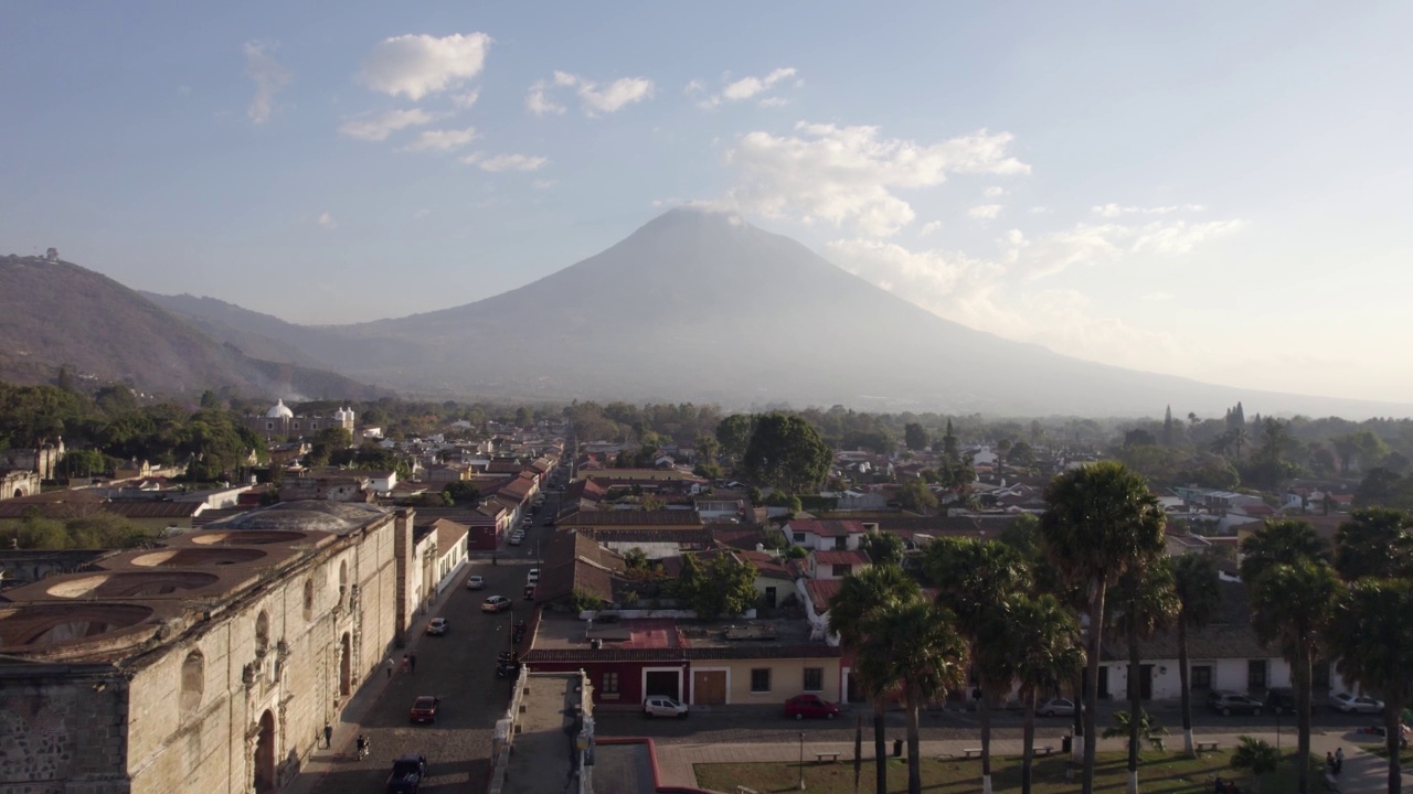 在阳光明媚的一天，危地马拉安提瓜岛，可以看到死气沉沉的阿瓜火山、鹅卵石街道和屋顶视频下载