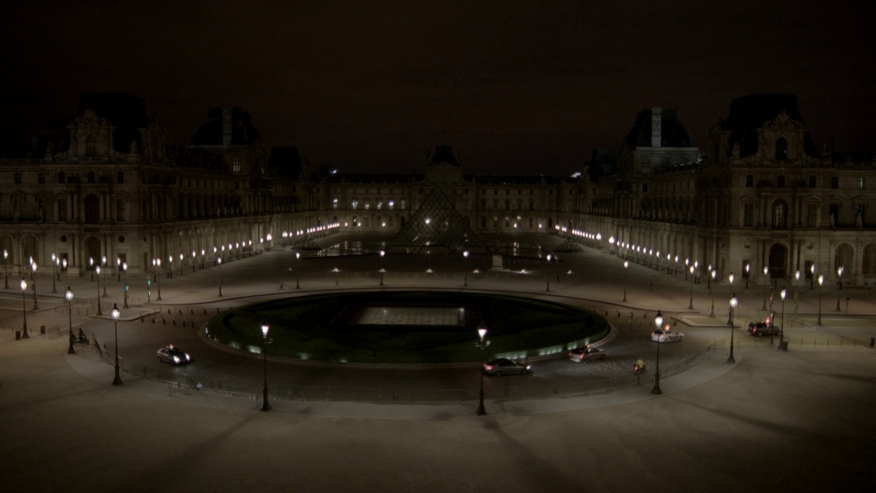 卢浮宫博物馆和玻璃金字塔的广角。汽车行驶在杜卡鲁塞尔广场交通圈在博物馆前可见。博物馆的灯都熄了。视频素材