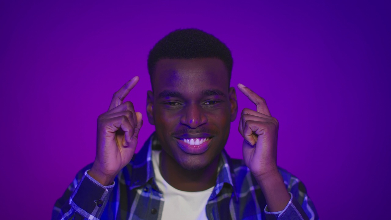一个黑人在紫色的背景下用手指指着他的头视频下载