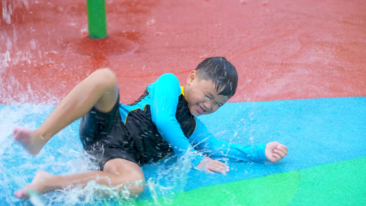 亚洲男孩在游泳池和水上公园玩水花视频下载