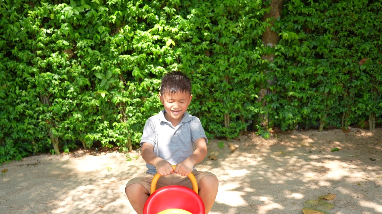 亚洲孩子在户外操场玩秋千、跷跷板等活动。户外学习理念，发现与快乐视频素材