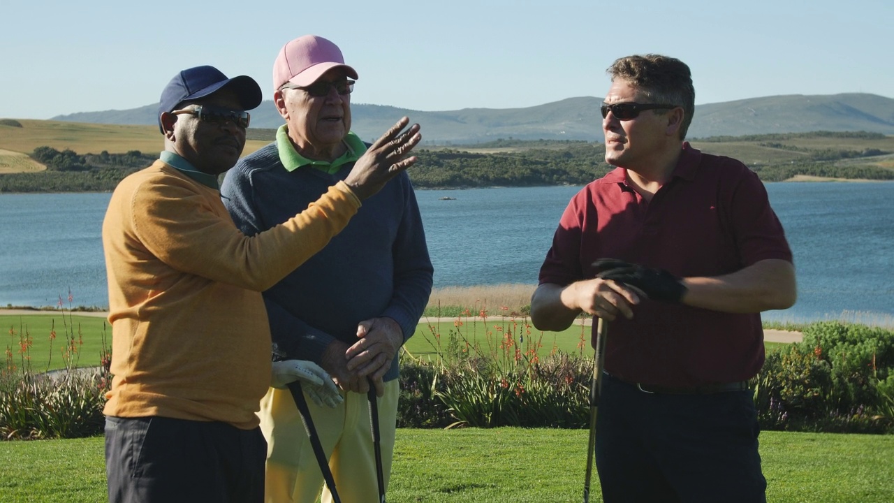 男性高尔夫球手在阳光明媚的湖边高尔夫球场上交谈和准备视频下载