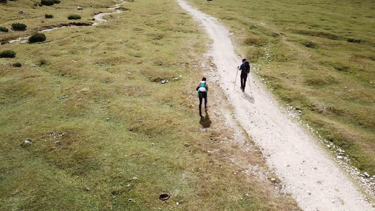 一对夫妇沿着一条穿过意大利白云石山谷的砾石小路徒步旅行。四周是高耸的山峰。石头和原始的景观。偏僻荒凉的地方自由的探索视频素材