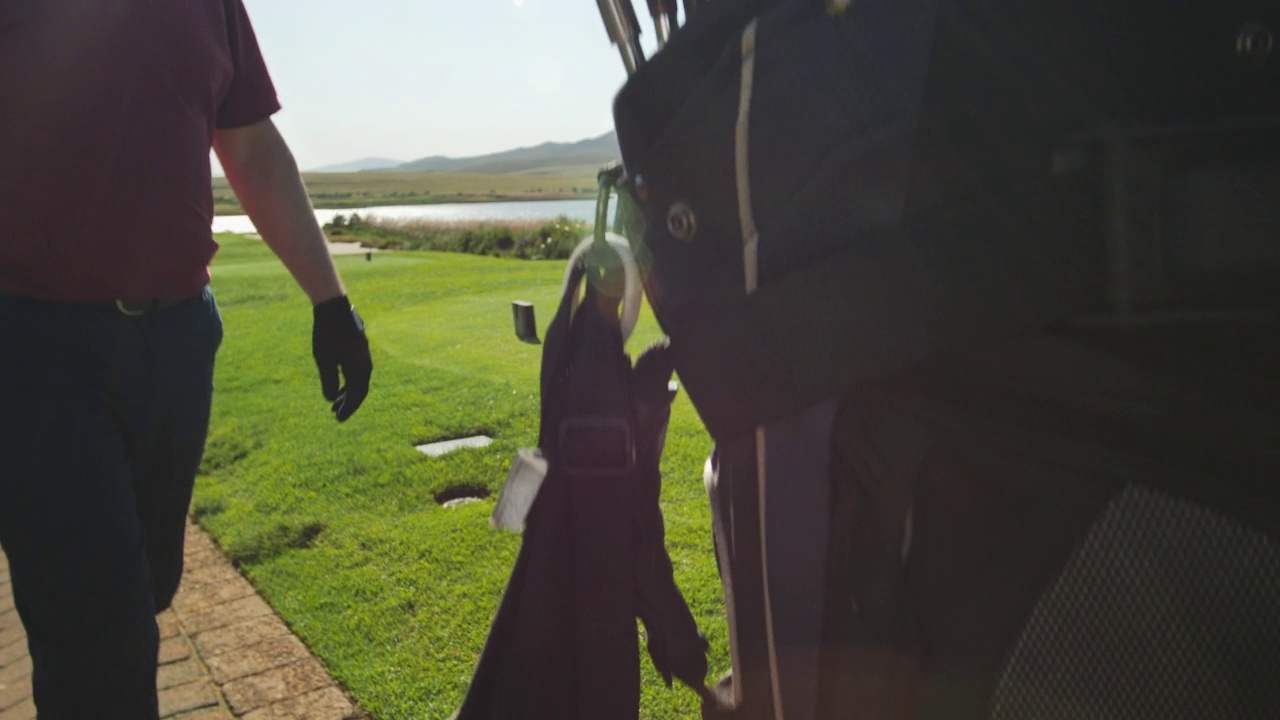 男性高尔夫球手选择高尔夫球俱乐部从袋在阳光高尔夫球场视频下载