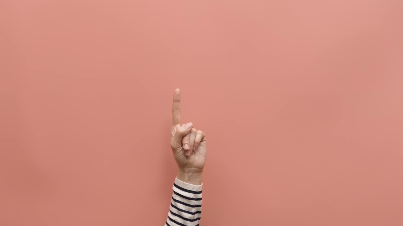 女性举起手，手指指向空的粉红色背景。沟通不用说话，手势概念视频素材
