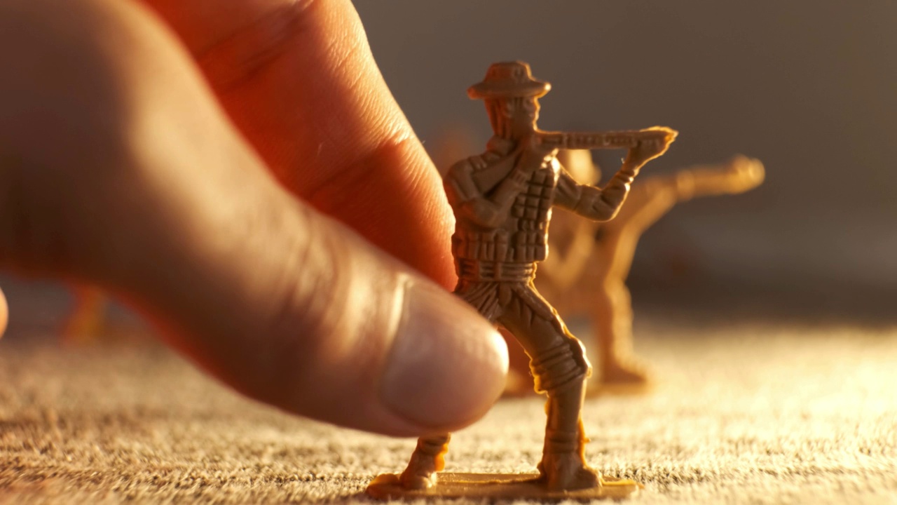 在假想的战场上，一只人的手将一个玩具士兵向前移动视频下载