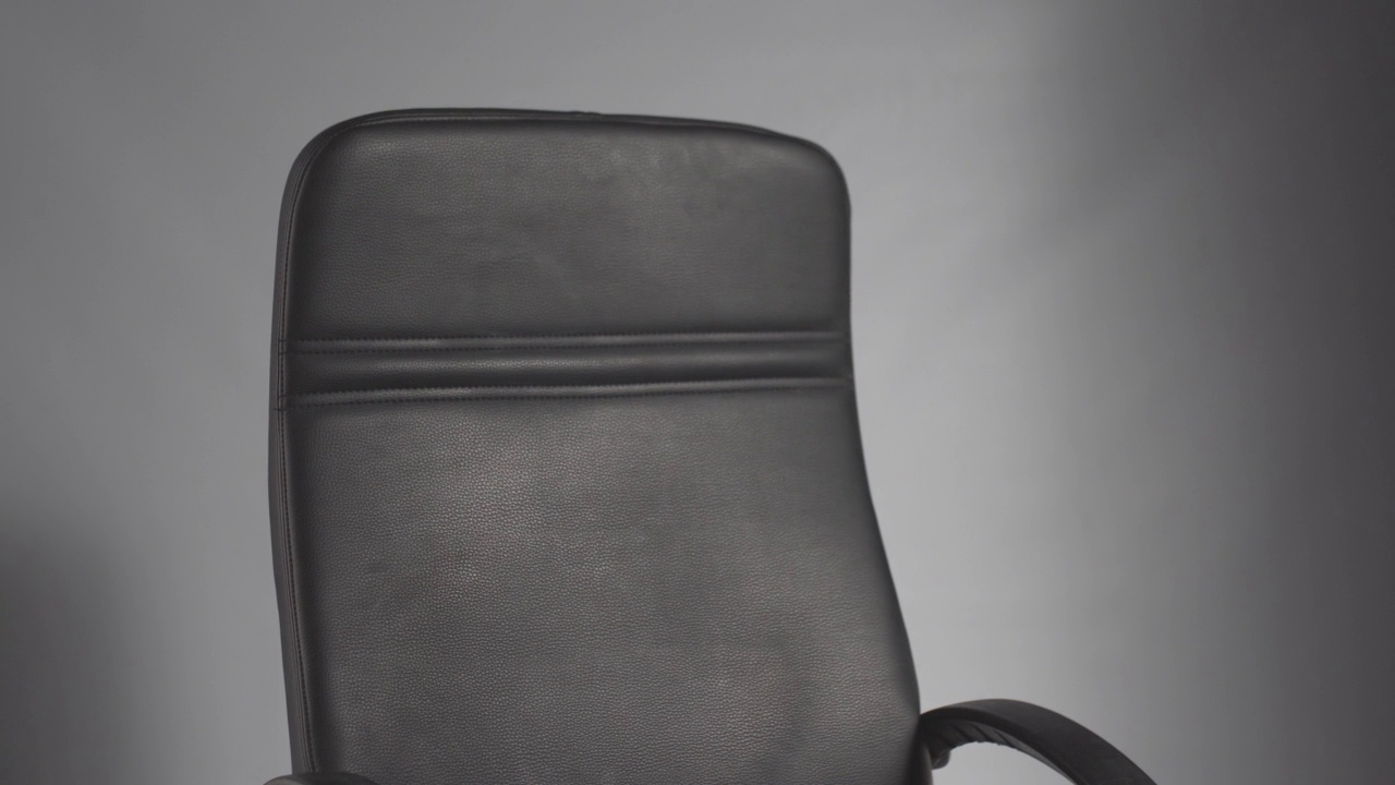 黑色办公椅在灰色背景上旋转视频下载