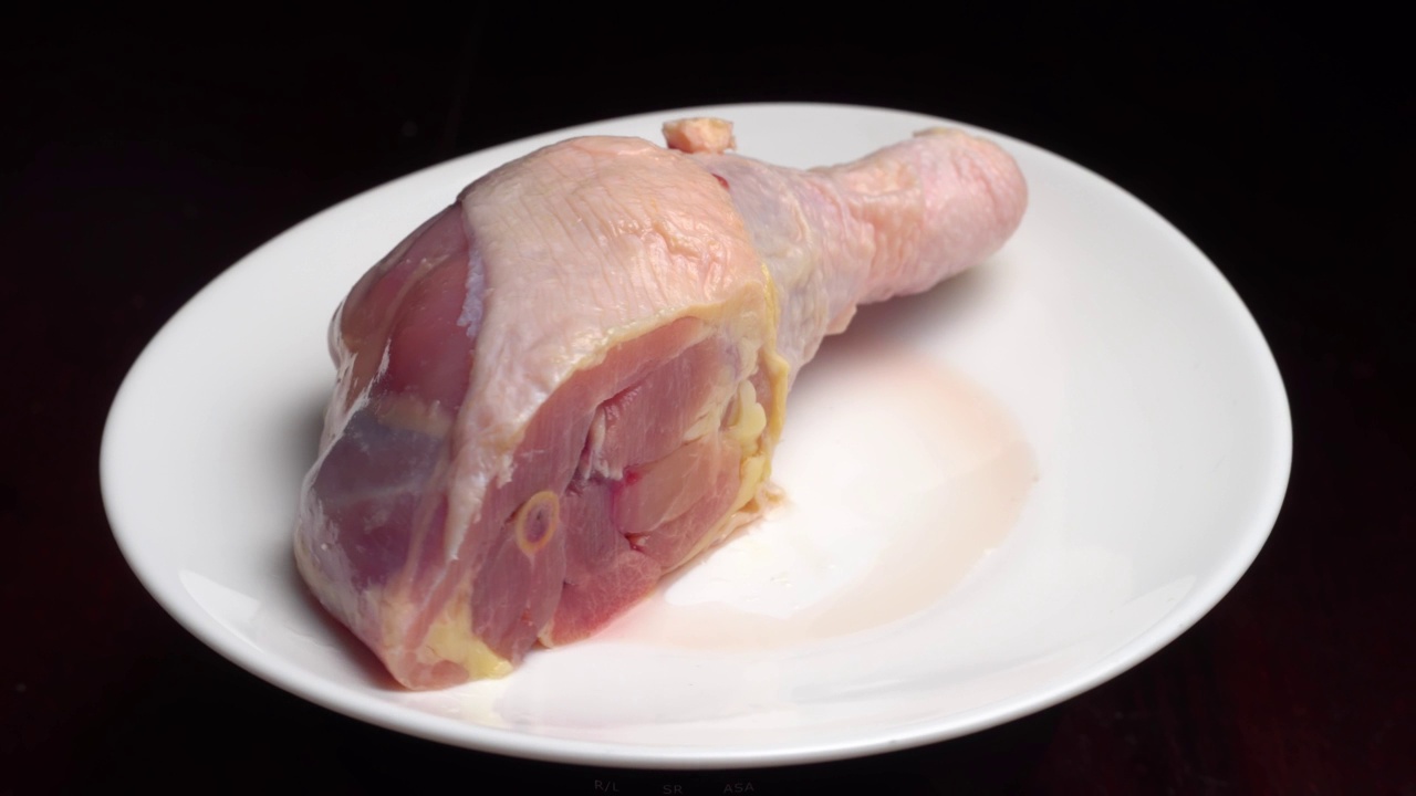 鸡腿或有胫骨的鸡腿放在白色盘子上，在转盘上旋转视频下载