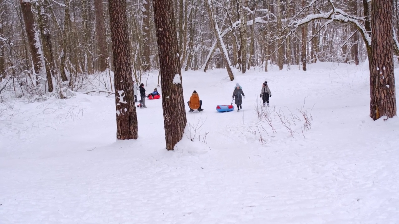在一个下雪的冬天，爸爸和女儿骑着雪车下山。他们坐在同一个雪橇上。冬季家庭娱乐，情绪高涨视频素材