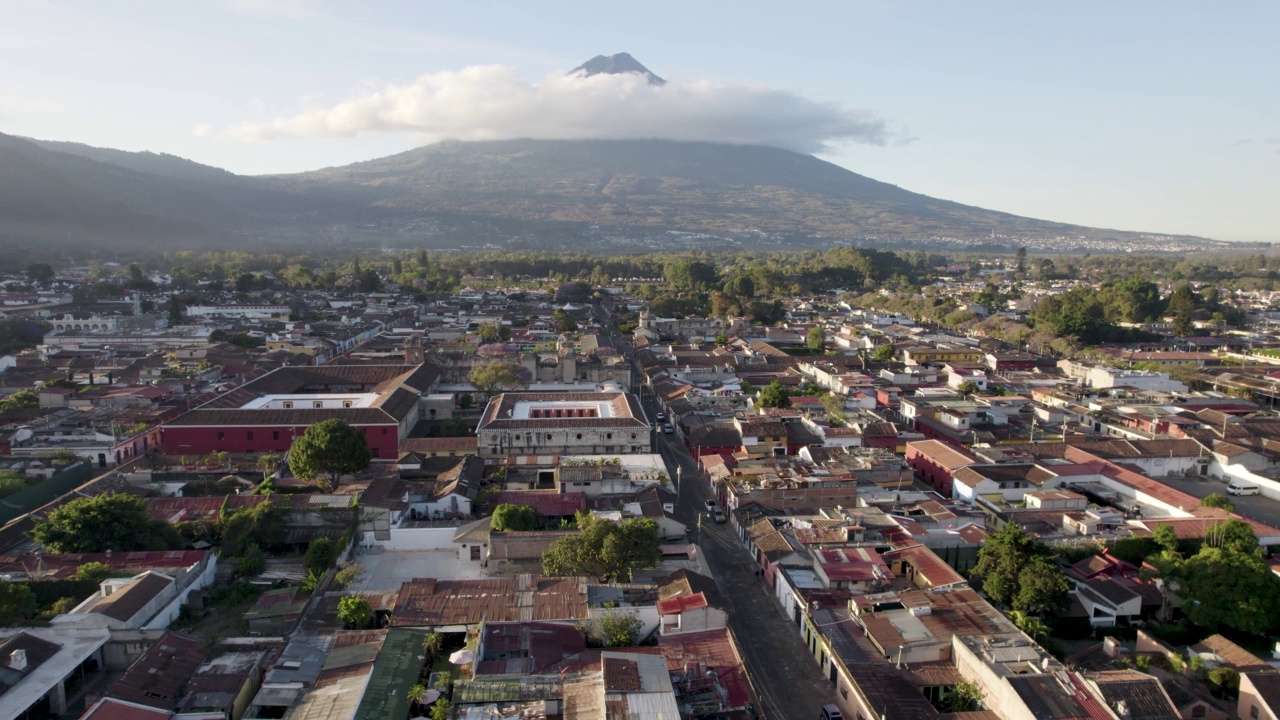 在阳光明媚的一天，危地马拉安提瓜岛，可以看到死气沉沉的阿瓜火山、鹅卵石街道和屋顶视频素材