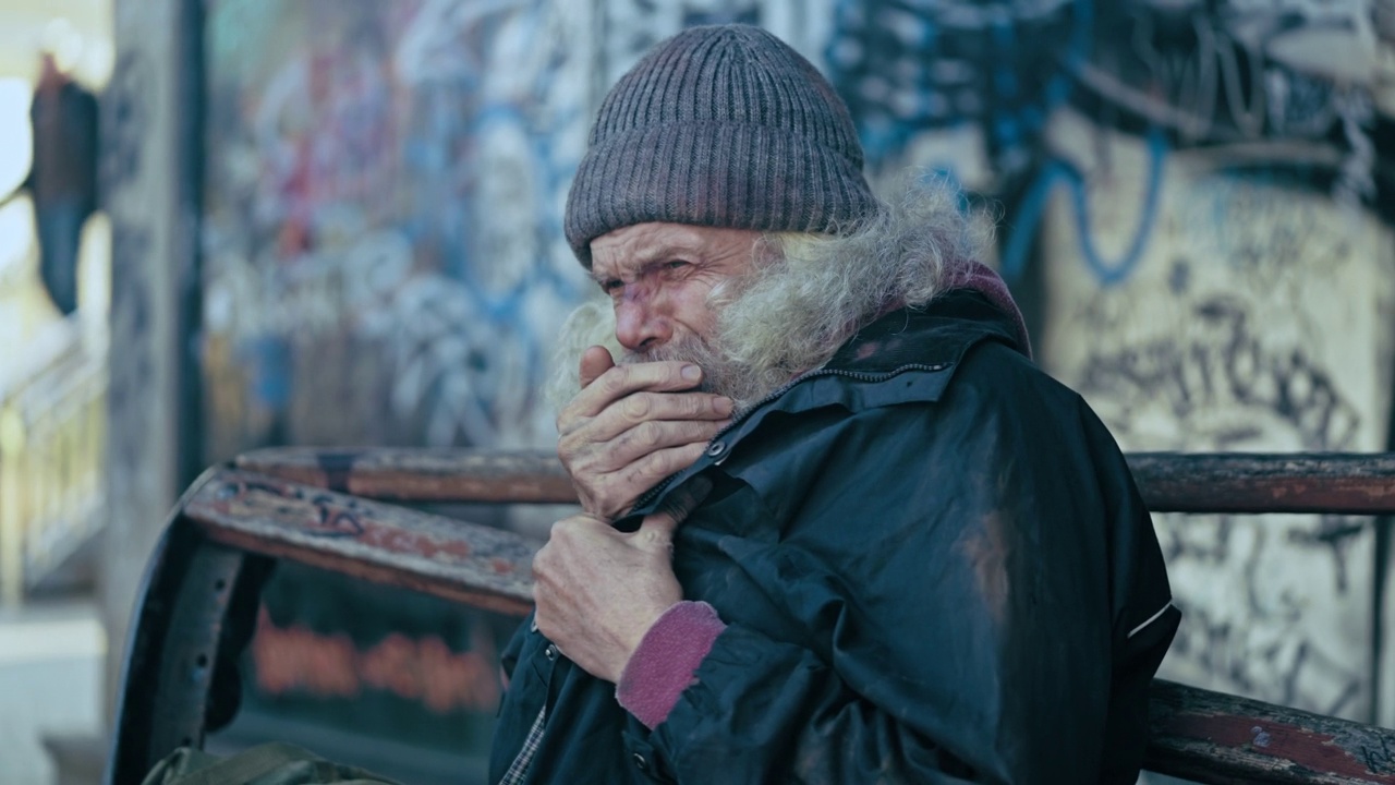 可怜的老男人穿着脏衣服咳嗽，试图取暖，无家可归视频下载