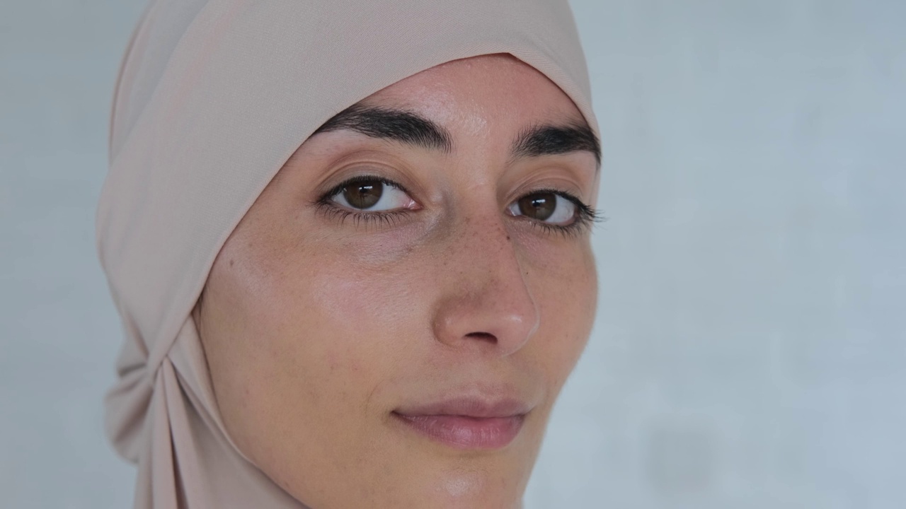年轻漂亮的穆斯林女子自信地微笑着，戴着伊斯兰教的头巾，脸上露出快乐可爱的表情。根据伊斯兰教法，女性的生活受到权利和自由的限制视频下载