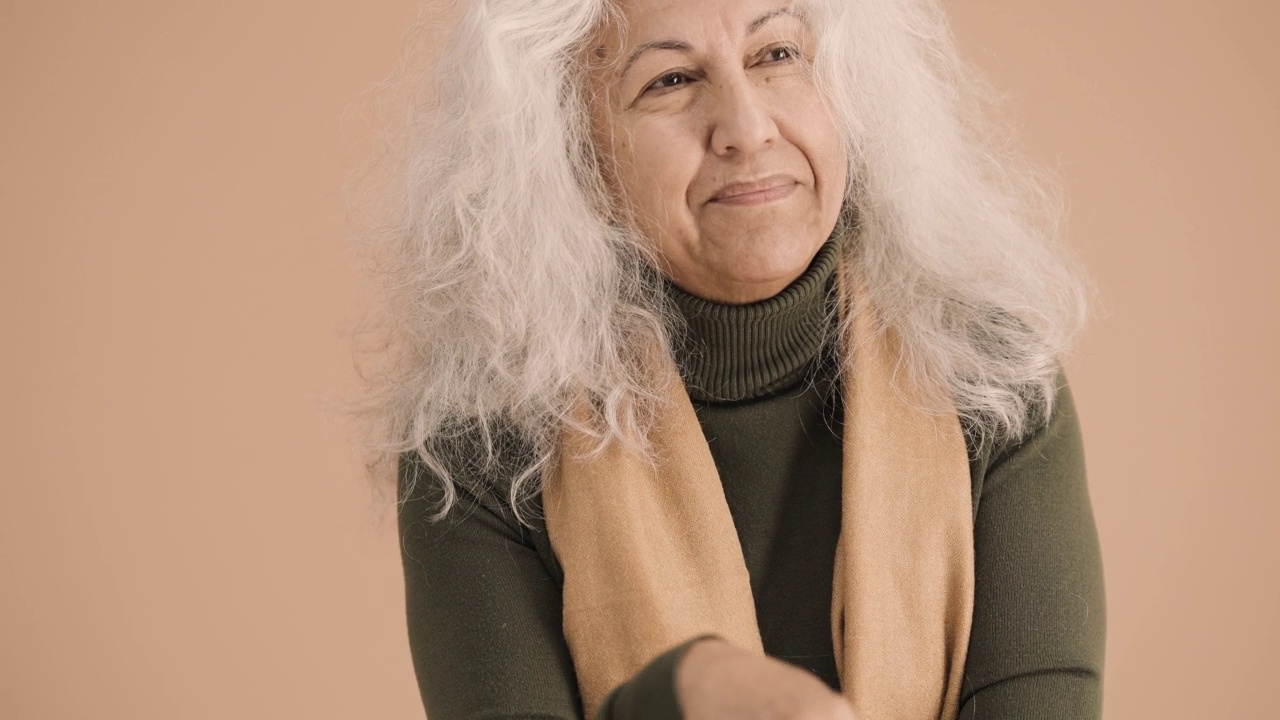 一位老妇人在棕色的背景上摸着脸视频素材