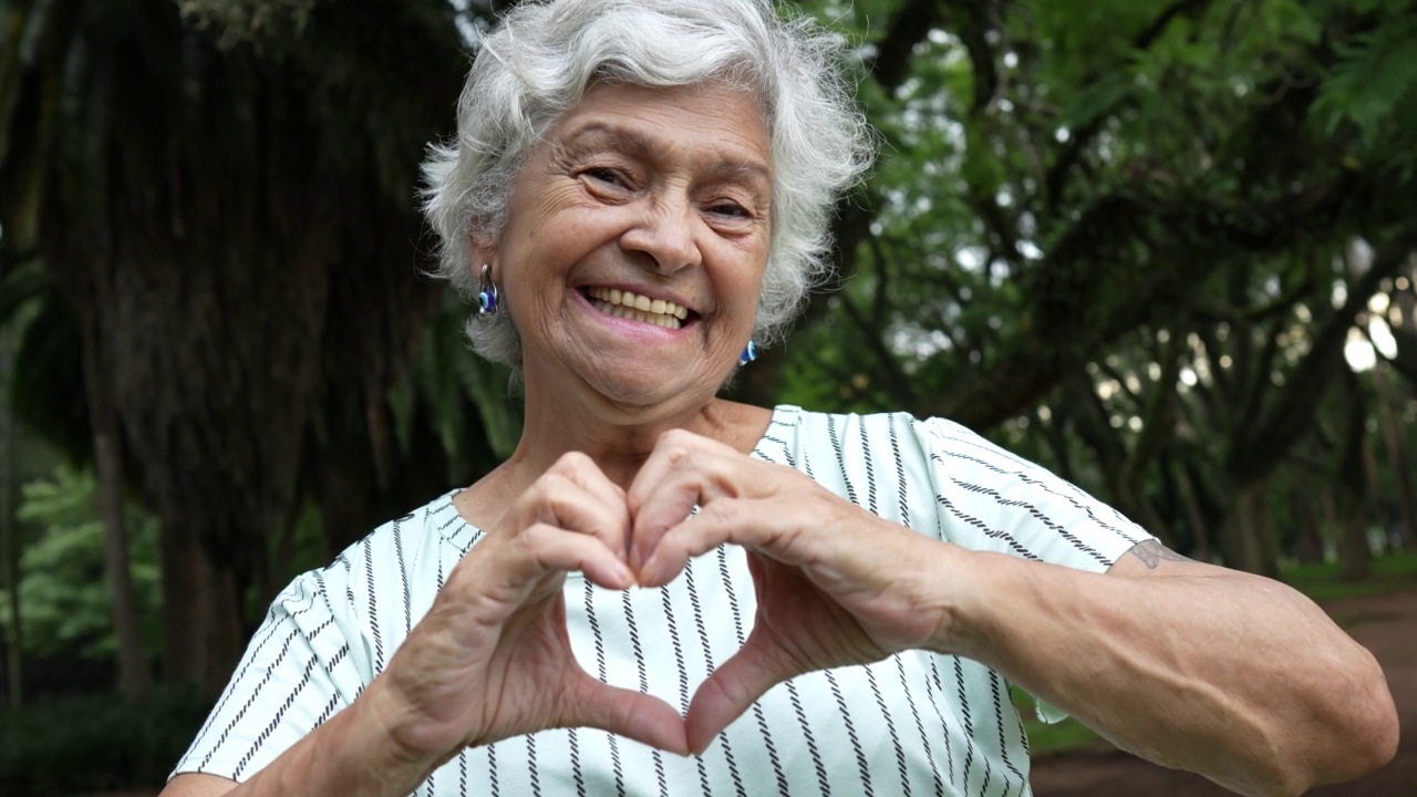 一位年长的女士用她的手做了一个心形的象征视频素材