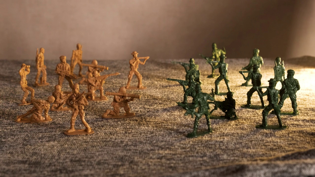 在闪烁的红光下，米色和绿色的塑料玩具士兵相对站着。一片乌云笼罩着战场视频下载