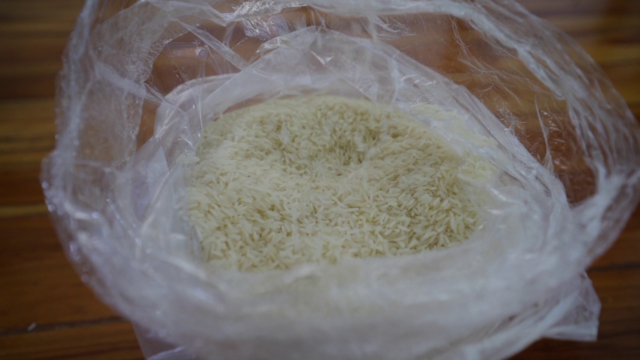 泰国大米缓缓落下。在农村用塑料袋装着生米粒视频下载