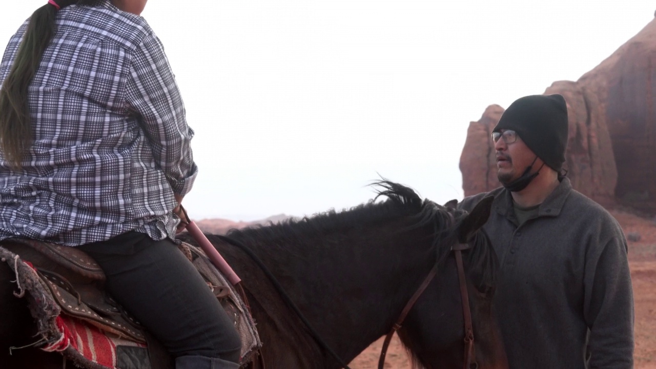 一位纳瓦霍男女在抚摸一匹马，而这匹马是一位坐在马上的女性视频下载