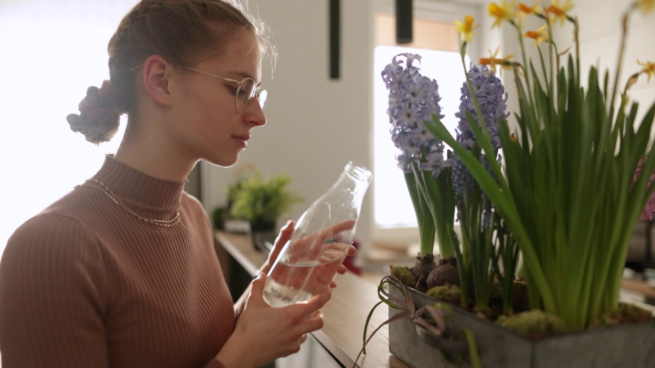 十几岁的女孩在花盆里浇春天的花。视频下载