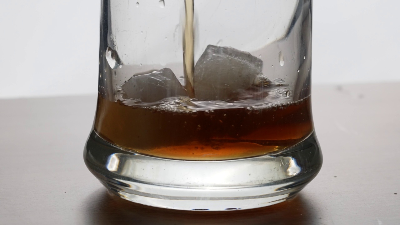 一个男人在往威士忌里加冰。酒精概念，白色背景，混合冰和威士忌视频下载