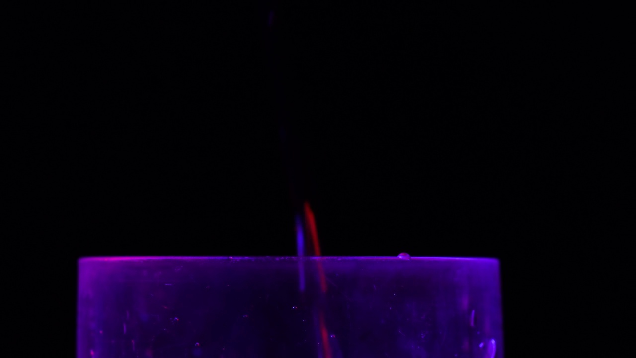 在迪斯科舞厅，霓虹灯下倒酒。彻夜狂欢的概念，酗酒和醉酒的概念视频下载