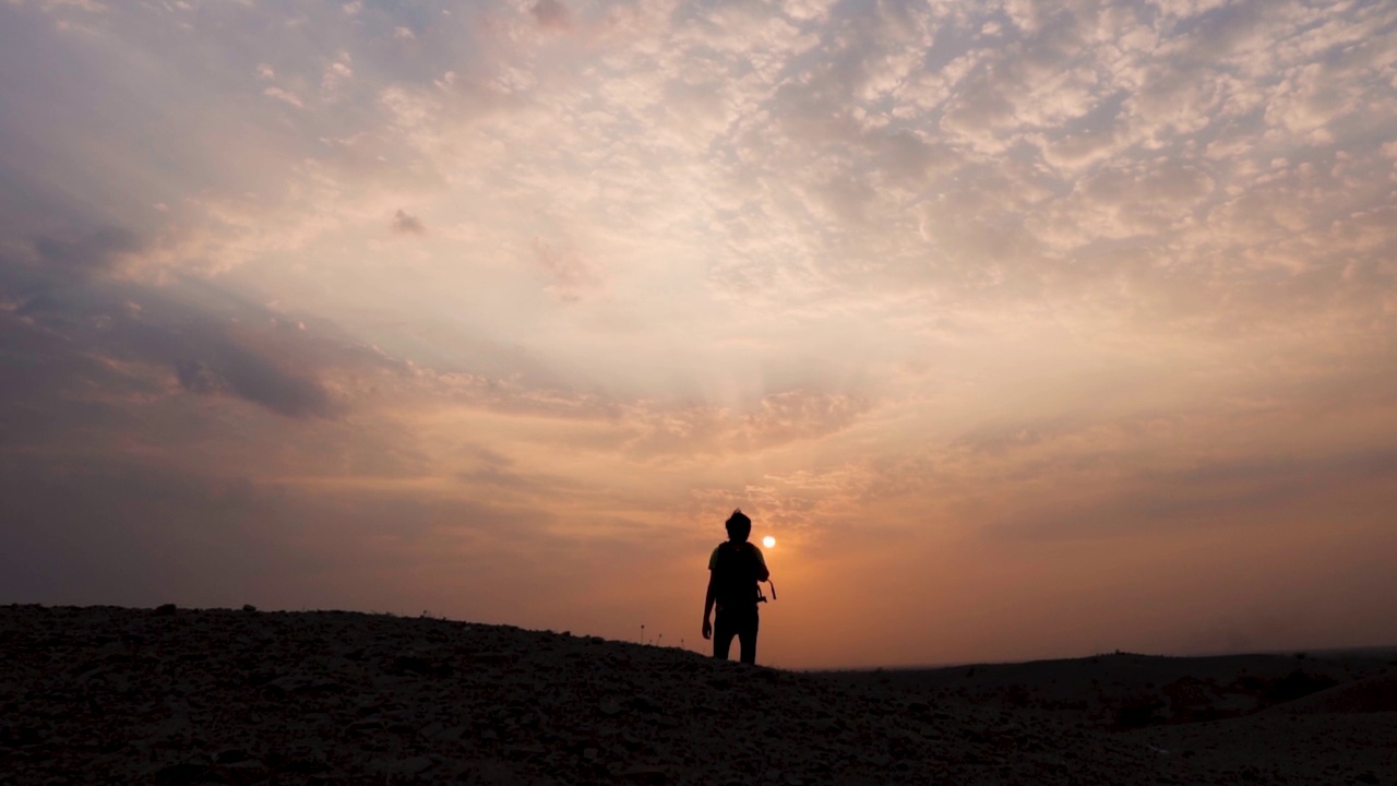 一个印度徒步旅行者在日落时凝视太阳的剪影。人们从山上看美丽的日落。自然背景视频素材
