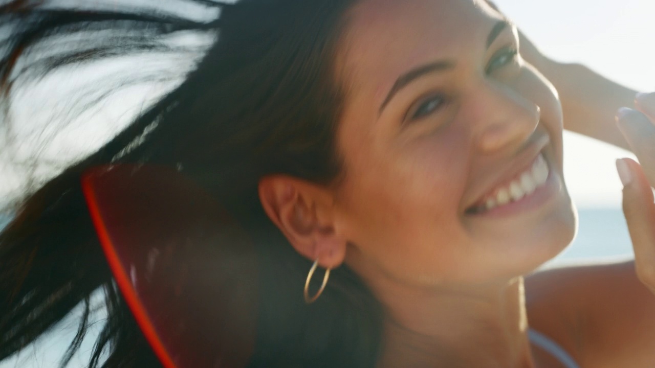 慢动作的年轻微笑的褐发女子是快乐的享受一个夏天的假期在一个阳光灿烂的日子，在海滩上的海。视频下载